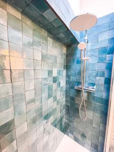 uma casa de banho com um chuveiro com azulejos azuis em L'AUTHENTIQUE - Sur le Port - Parking - Wifi em Cassis