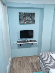 Zimmer mit einem TV auf einem Regal an der Wand in der Unterkunft LAVİNYA PENSİON in Kusadası