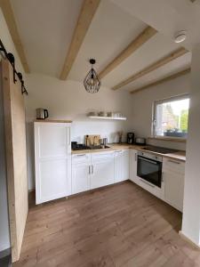 a kitchen with white cabinets and a wooden floor at Ferienwohnung Hajü in Herrischried