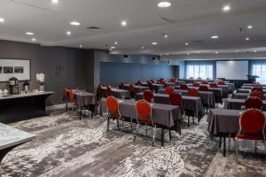 una sala de conferencias con mesas, sillas y una pantalla en Hotel Manoir Victoria en Quebec