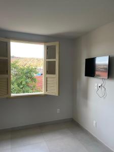 Cette chambre blanche dispose d'une télévision et d'une fenêtre. dans l'établissement Casa Ouro no centro de Diamantina, à Diamantina