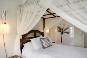 a bedroom with a white bed with white curtains at Little Good Harbour in Saint Peter