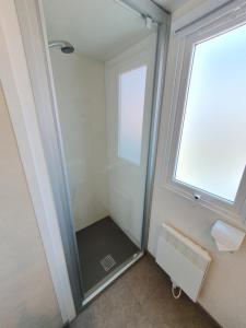 a walk in shower in a bathroom with a window at Campingland Ostsee - Mobilheim 155Meerluft in Schashagen