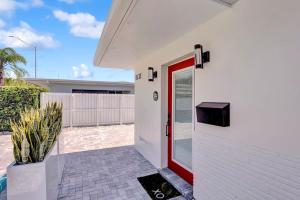 eine rote Tür an der Seite eines weißen Hauses in der Unterkunft Soleil @ Casa Del Sol in Fort Lauderdale