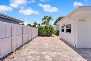 a house with a white fence and a driveway at Soleil @ Casa Del Sol in Fort Lauderdale