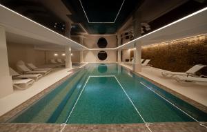 a swimming pool in a hotel with lounge chairs at Sport Club Residences & Spa in Crans-Montana