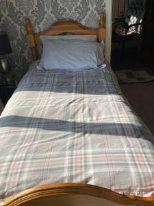 a bed with a plaid comforter on it at Junes cosy apartment in Mayo