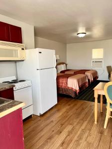 Habitación pequeña con cama y nevera blanca. en Chief Motel en Keokuk