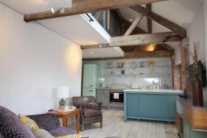 a living room with a couch and a kitchen at The Hayloft - Cheshire in Crewe