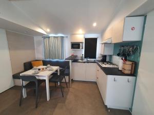 a small kitchen with a white table and chairs in a room at Campingland Ostsee - Mobilheim A2Meeresbriese in Schashagen