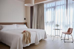 sypialnia z dużym białym łóżkiem i krzesłem w obiekcie Hotel Trina 20 w mieście Palas de Rei 