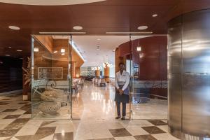 una mujer parada junto a una puerta de cristal en un vestíbulo en Hotel de Convenções de Talatona, HCTA en Luanda