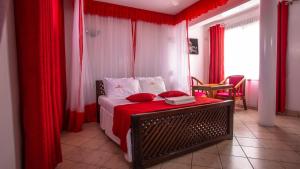 a bedroom with a bed with red curtains at Hotel Windsor-Mombasa in Mombasa