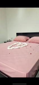 Una cama rosa con sábanas rosas y almohadas. en Dar toumana djerba, en Taguermess