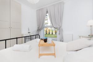a white bedroom with two beds and a table at Gdynia Nasypowa Apartments with Parking by Renters in Gdynia