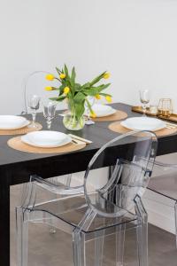 a dining table with a clear chair in front of it at Gdynia Nasypowa Apartments with Parking by Renters in Gdynia