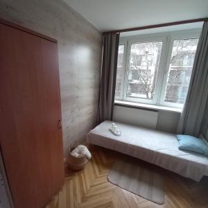 a small room with a bed in front of a window at Regem Pokoje Złota in Warsaw