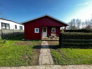 a red shed with a porch in a yard at Lodge on the campsite in Oostvoorne
