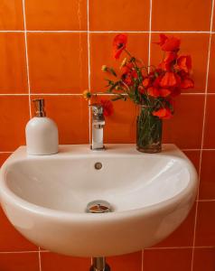 a white sink with a vase of flowers on it at La Mansarda degli Ulivi in Portoferraio