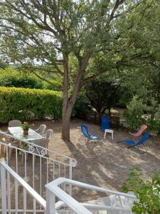 eine Terrasse mit Stühlen, einem Tisch und einem Baum in der Unterkunft le soleil du verdon in Baudinard