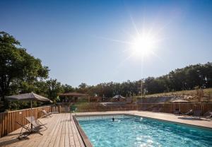una piscina con sillas, sombrilla y sol en Huttopia Pays de Cordes sur Ciel, en Albi