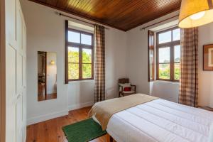 a bedroom with a bed and two windows at Casa do Lamaçal - Minho's Guest in Guardizela