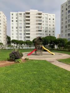 a playground with a slide in a park with tall buildings at Departamento Edificio Terrazas de Sol in La Serena