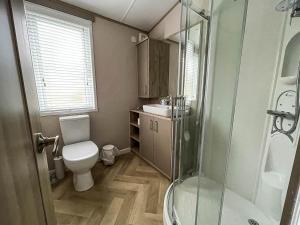 a bathroom with a toilet and a glass shower at Beautiful Lodge With Decking At Azure Seas In Suffolk, Sleeps 6 Ref 32217og in Lowestoft