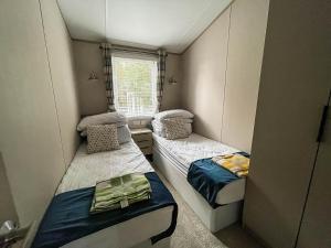 a small room with two beds and a window at Beautiful Lodge With Decking At Azure Seas In Suffolk, Sleeps 6 Ref 32217og in Lowestoft