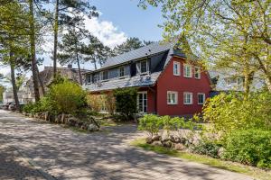 a red house with a gray roof on a street at Strandleben 10 - Louis Douzette in Ahrenshoop