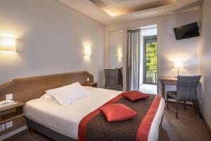 a hotel room with a bed and a desk and a window at Logis Hôtel Restaurant Le Mont Aigoual in Meyrueis