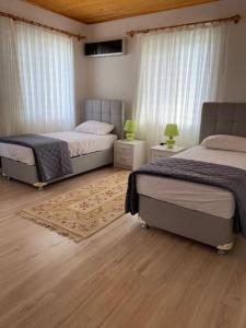 1 dormitorio con 2 camas y alfombra en Doğanın kalbinde havuzlu villa, en Koycegiz