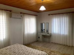 1 dormitorio con cortinas blancas, 1 cama y vestidor en Doğanın kalbinde havuzlu villa, en Koycegiz