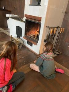 dos chicas sentadas en el suelo frente a una chimenea en Jeleńczówka Alte Dorfschule, en Parchowo