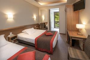 a hotel room with two beds and a television at Logis Hôtel Restaurant Le Mont Aigoual in Meyrueis