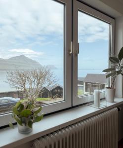 un rebord de fenêtre avec des plantes et une fenêtre avec vue dans l'établissement Serenity by the Sea / 3-BR House / Sea View, à Syðrugøta