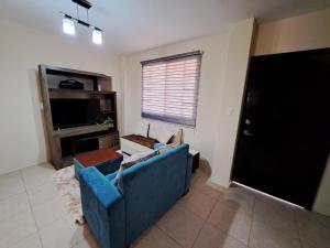sala de estar con sofá azul y TV en Casa Vacacional en Conjunto Privado, en Manta