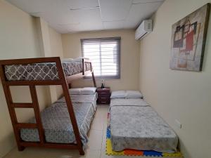 a room with three bunk beds and a window at Casa Vacacional en Conjunto Privado in Manta
