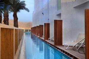 a pool at a hotel with chairs and palm trees at Herbert Samuel The Reef Eilat in Eilat