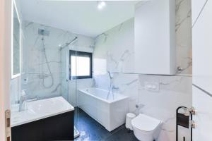 ein weißes Badezimmer mit einer Badewanne, einem WC und einem Waschbecken in der Unterkunft CROWONDER Adriatic Premium Villa Vodice near the Beach in Vodice
