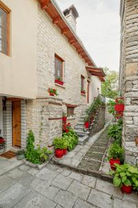 un bâtiment en pierre avec des plantes en pot devant lui dans l'établissement Archontiko Rapti Stone Traditional House, à Monodendri