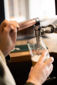 a person is drinking a glass of beer at Masons Arms Amble in Amble