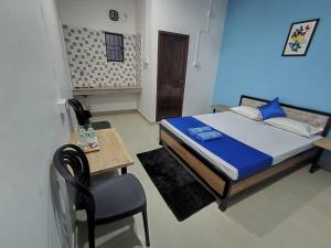 a bedroom with a bed and a table and a chair at The Corner Inn (Lodge) in Guwahati