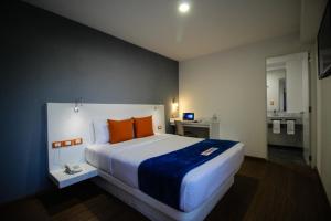Hotel Star Express Puebla في بوبلا: غرفة نوم مع سرير كبير مع وسائد برتقالية
