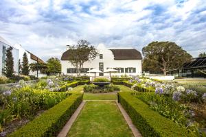 a garden in front of a white house at The Homestead at Hazendal Wine Estate by NEWMARK in Stellenbosch
