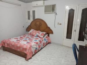 um pequeno quarto com uma cama e uma cabeceira em madeira em Manial El roda no Cairo