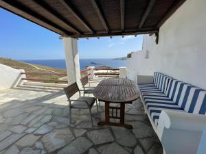 un patio con mesa, sillas y el océano en Cycladic style Maisonette with staggering sea view en Agios Sostis Mykonos