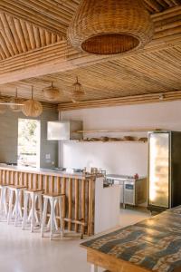 a kitchen with wooden ceilings and a bar with stools at Happiness Hostel Siargao in General Luna