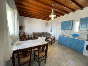cocina y comedor con armarios azules y mesa en Cycladic style Maisonette with staggering sea view en Agios Sostis Mykonos