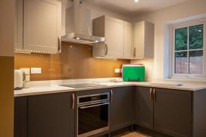 una cocina con armarios grises y una caja verde en la encimera en Breckland Thatched Cottage, en Hockwold cum Wilton